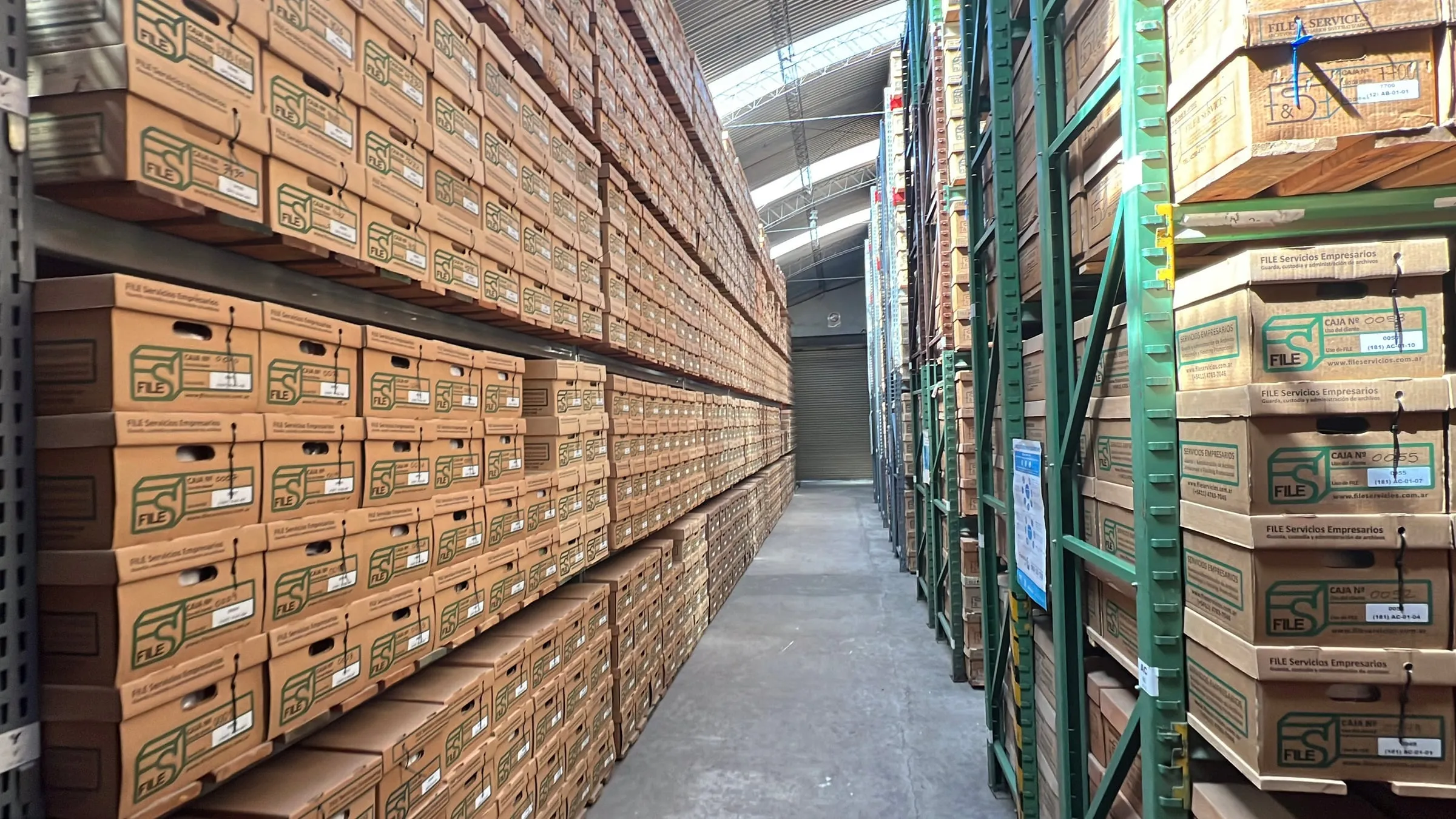 Pasillo largo del depósito con estanterías de cajas a ambos lados