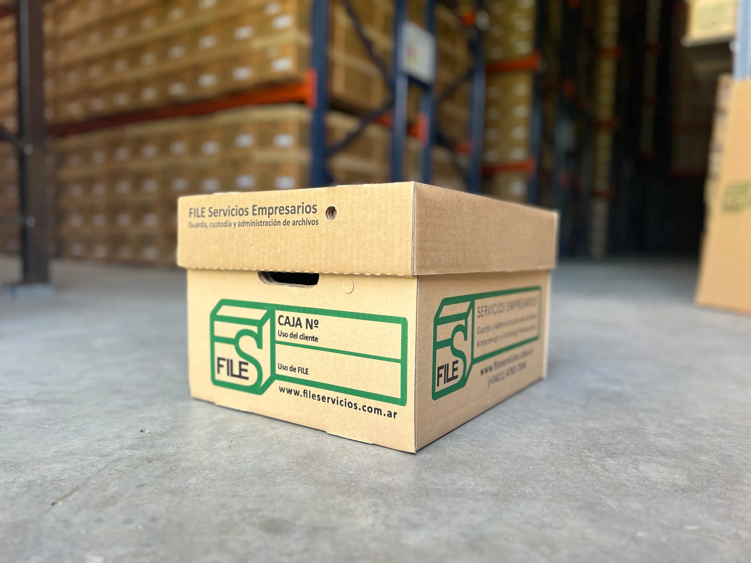 Caja FILE sobre el piso del depósito, con estanterías al fondo