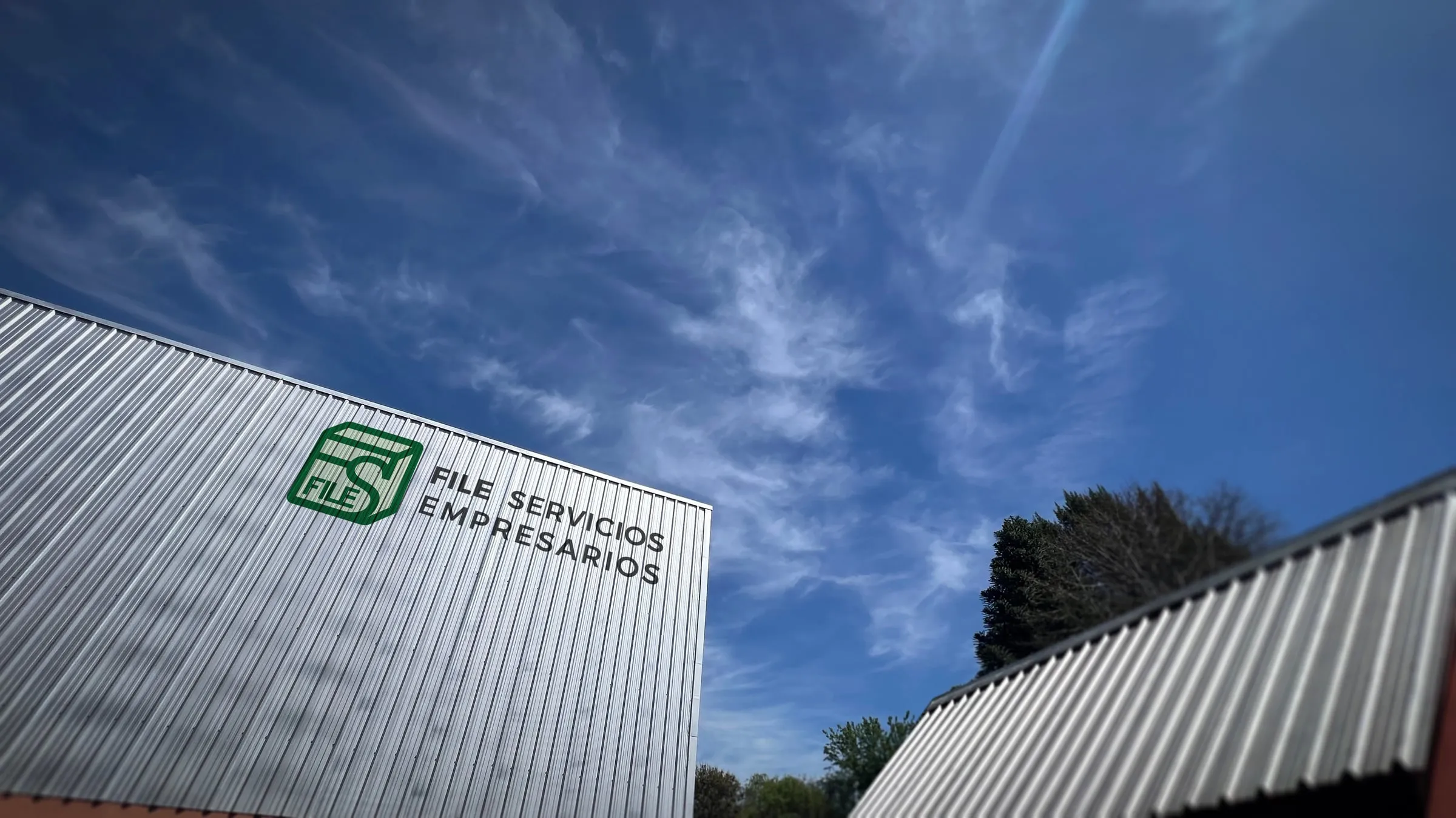 Fachada del depósito con el logo de FILE bajo un cielo despejado